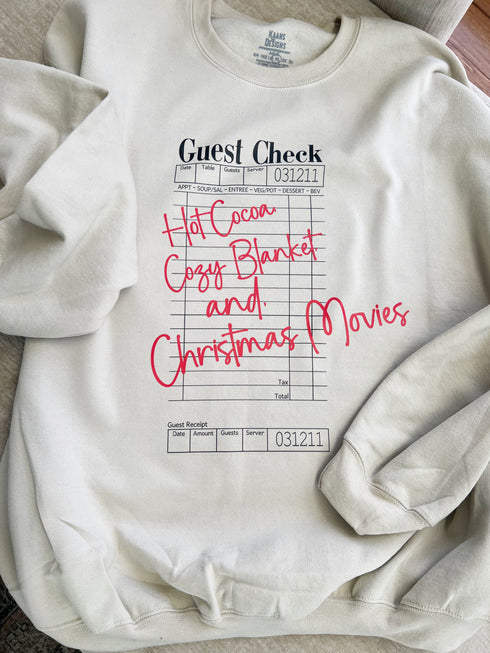 christmas theme sweatshirt that is a guest check that says hot coacoa cozy blanket and christmas movies.