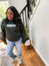 black woman wearing forest green sweatshirt in her home with a cute snake plant in the background and beautiful white aesthetic home