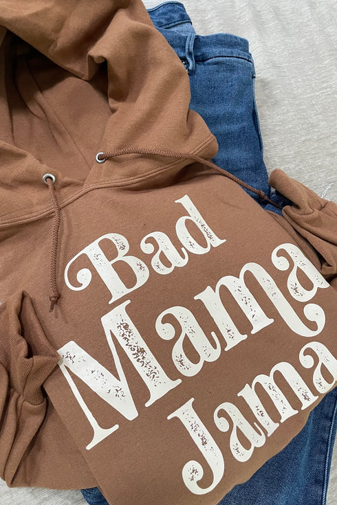 flat lay of brown hoodie with cream ink screen print design that says bad mama jama, laying on some cute everyday blue jeans for a cozy outfit for moms with a cute saying