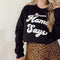 women modeling behind a white background in pullover sweatshirt in leopard print skirt with the pullover tucked in