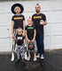 family matching in halloween shirts creating cute costume for hallowen night, reminds you of the adams family in modern day screen print design tshirts are mummy deaddy boo zombae holding a pumpkin bag for candy mom in a witch hat and dad holding a skull